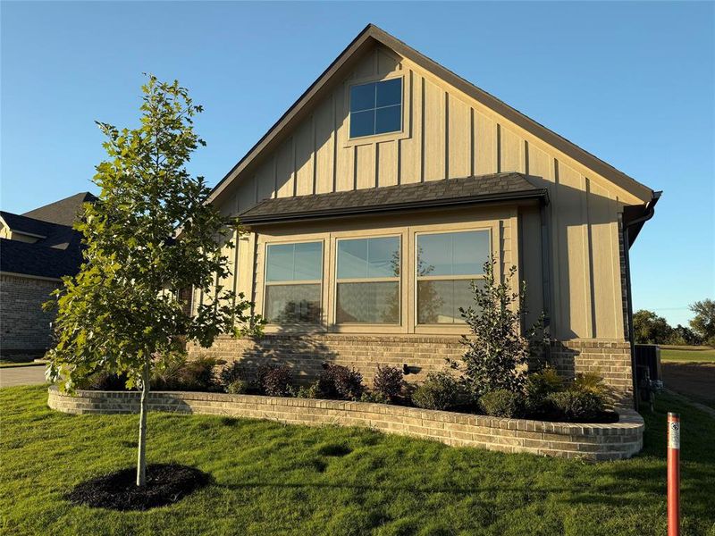 View of side of home with board and batten siding, a lawn, and brick siding View of side of home with board and batten siding, a lawn, and brick siding