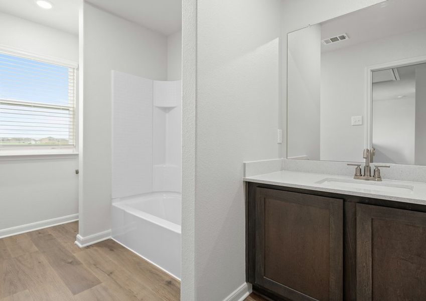 The secondary bathroom has a large vanity space and shower-tub combo.