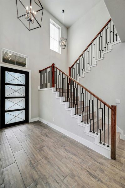 Foyer featuring baseboards, stairs, a chandelier, and wood finished floors