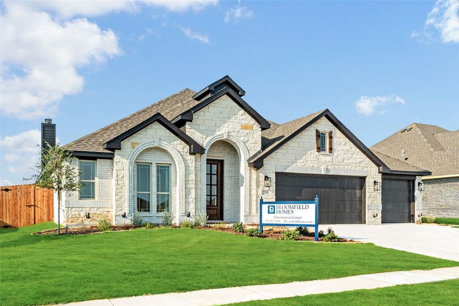 Single-story Bloomfield Homes model with stone exterior, arched entry, two-car garage, and green front lawn.