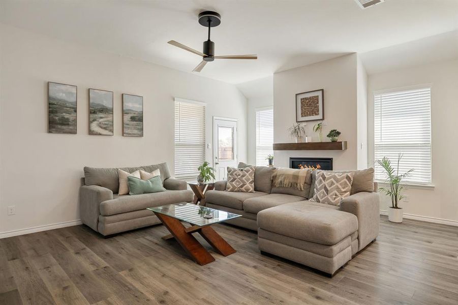 Living area featuring ceiling fan, wood finished floors, and a glass covered fireplace Living area featuring ceiling fan, wood finished floors, and a glass covered fireplace