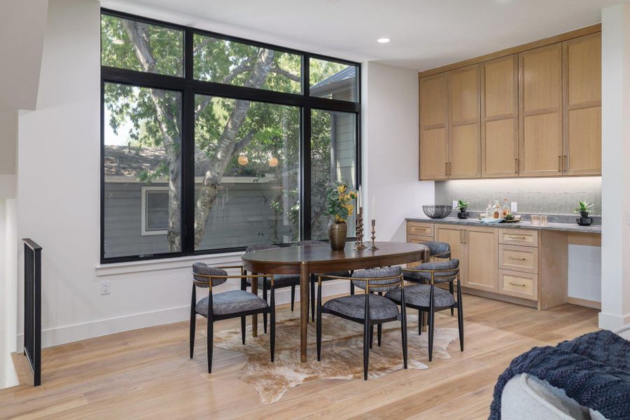 Expansive black-framed window, light wood-finish flooring, built-in cabinetry, stone countertop, and recessed lighting