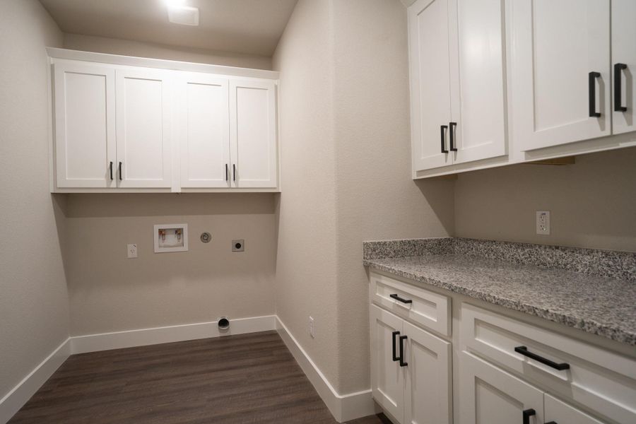 Laundry area with cabinet space, hookup for an electric dryer, washer hookup, dark wood-type flooring, and baseboards Laundry area with cabinet space, hookup for an electric dryer, washer hookup, dark wood-type flooring, and baseboards