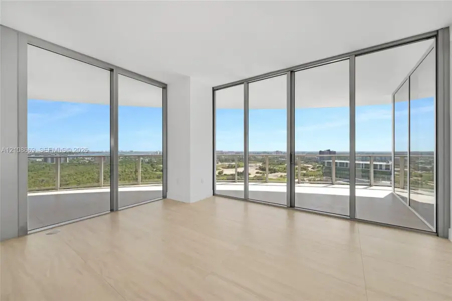 Floor-to-ceiling glass walls, wrap-around balcony, expansive exterior railing, and wood-finish flooring