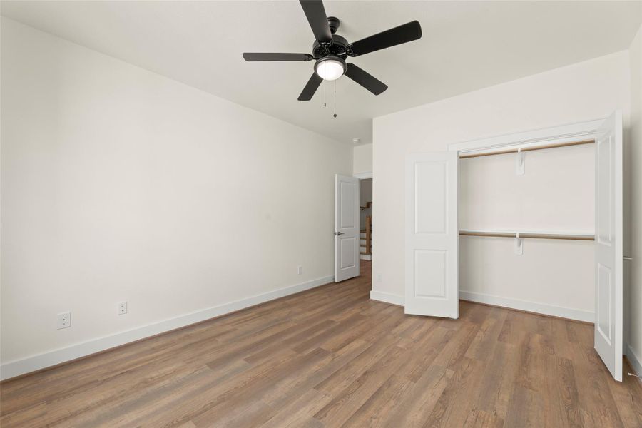 This room features a spacious layout with a ceiling fan, and a double-door closet. The walls are painted a neutral color, providing a bright and inviting space. Ideal for a bedroom or home office.