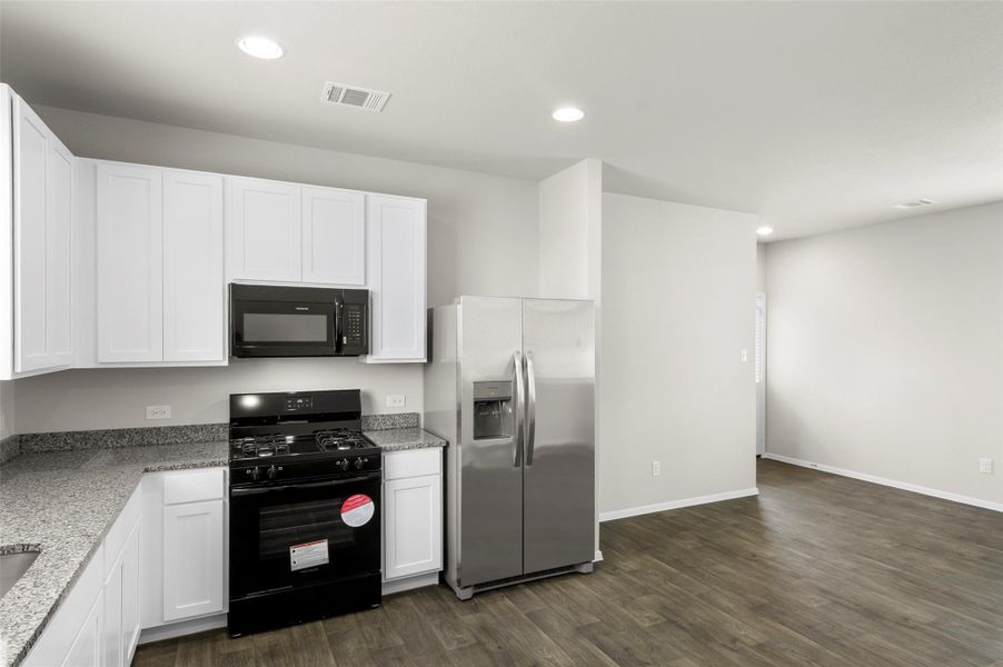 Kitchen featuring black appliances, white cabinets, dark wood-style floors, recessed lighting, and light stone counters Kitchen featuring black appliances, white cabinets, dark wood-style floors, recessed lighting, and light stone counters