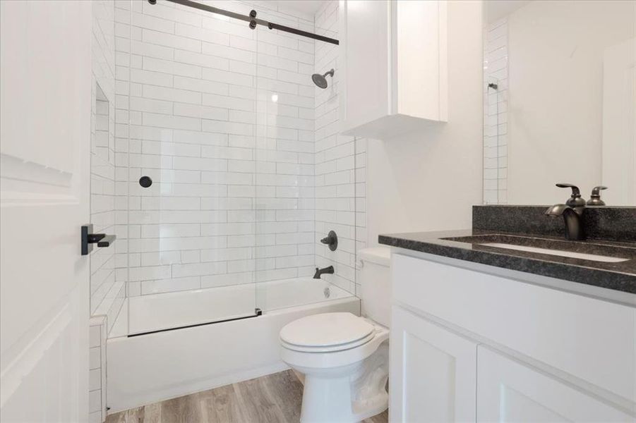 Full bathroom featuring bath / shower combo with glass door, vanity, and wood-type flooring