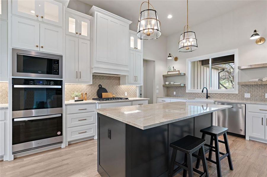 Kitchen with appliances with stainless steel finishes, white cabinetry, tasteful backsplash, and a kitchen island