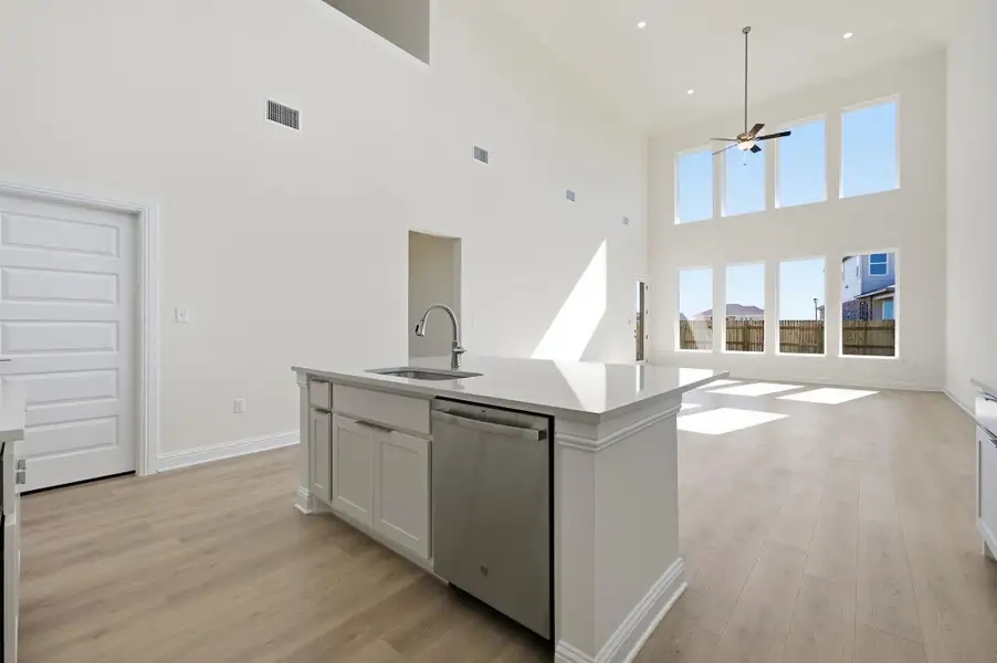 Kitchen with light wood-type flooring, stainless steel dishwasher, an island with sink, open floor plan, and white cabinets