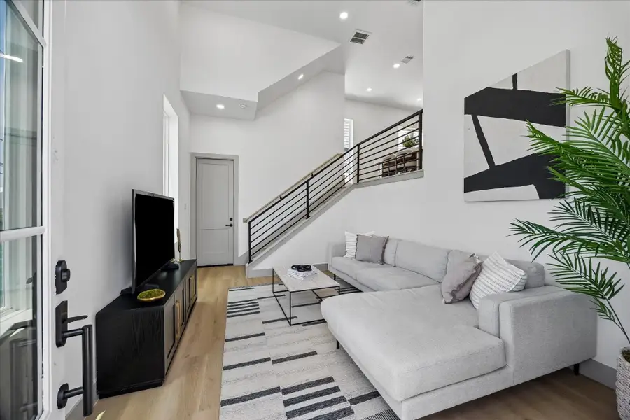 Towering ceilings and expansive windows fill the living room with natural light, creating an open space designed for both relaxing and entertaining. Towering ceilings and expansive windows fill the living room with natural light, creating an open space designed for both relaxing and entertaining.