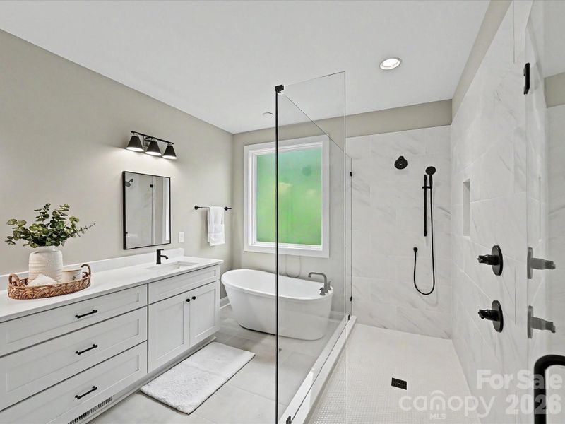 Luxurious primary bath offers a dual-sink vanity, oversized walk-in tile shower, and relaxing freestanding soaking tub.