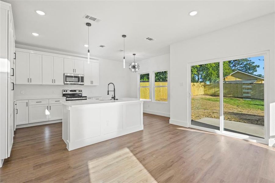 Kitchen featuring white cabinets, an island with sink, recessed lighting, appliances with stainless steel finishes, and pendant lighting