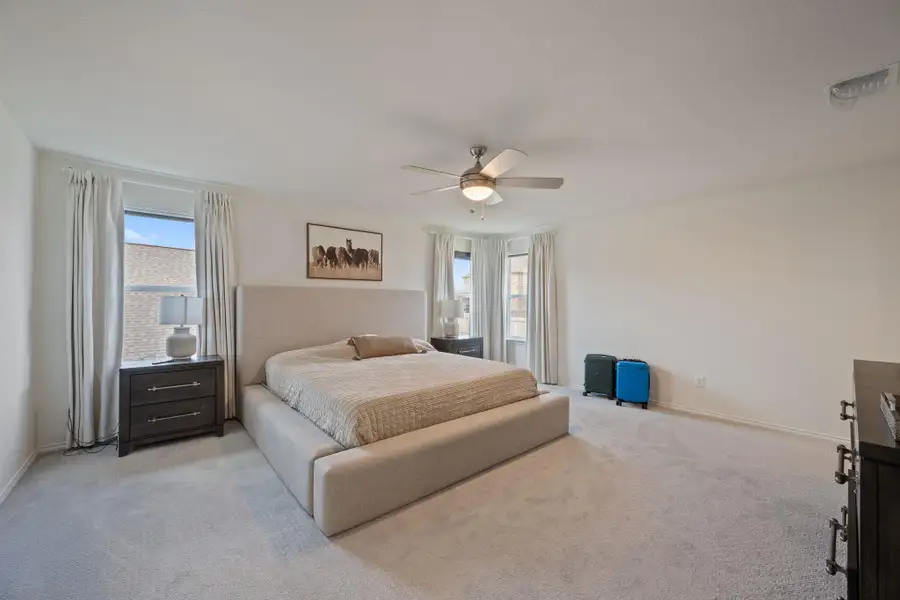 Carpeted bedroom with multiple windows and a ceiling fan Carpeted bedroom with multiple windows and a ceiling fan