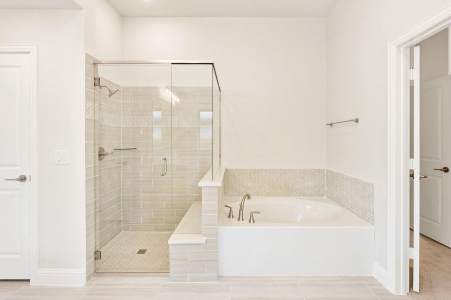 Master bathroom with glass-enclosed tile shower and soaking tub with herringbone tile surround