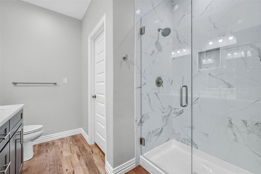 Bathroom with wood-type flooring, vanity, toilet, and walk in shower