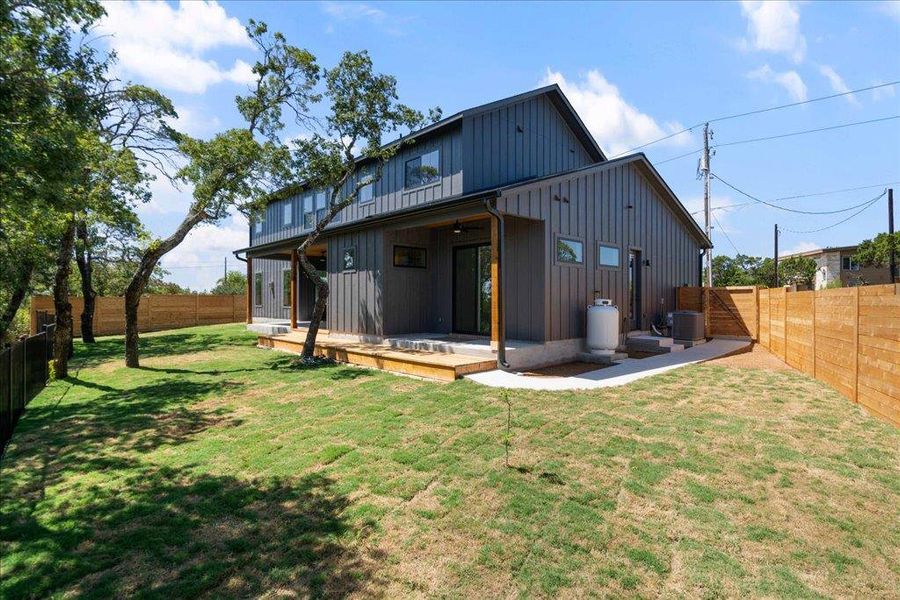 Rear view of property with board and batten siding, a fenced backyard, and a patio