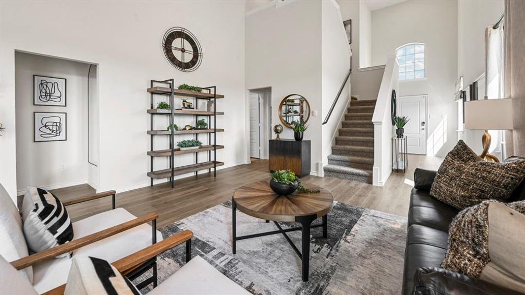 Living room featuring stairs, wood finished floors, and a towering ceiling Living room featuring stairs, wood finished floors, and a towering ceiling