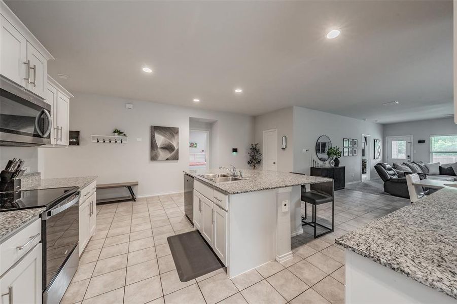Kitchen featuring white cabinetry, stainless steel appliances, speckled stone countertops, and tile flooring