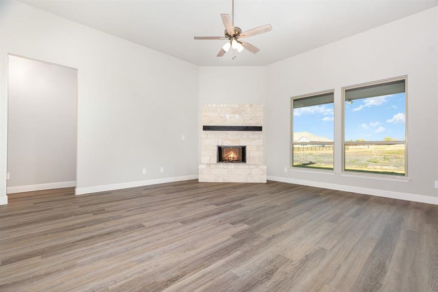 Unfurnished living room featuring wood finished floors, a fireplace, and a ceiling fan
