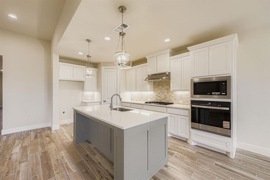 Kitchen featuring appliances with stainless steel finishes, tasteful backsplash, white cabinetry, hanging light fixtures, and recessed lighting
