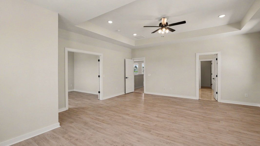 Primary bedroom with hardwood flooring and view of connected private study and en-suite bathroom