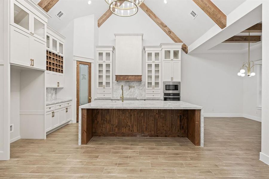 Kitchen featuring a large central island with wood paneling and a light-toned countertop