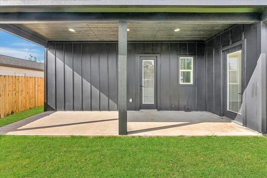 Back of property featuring board and batten siding, a patio, and a yard
