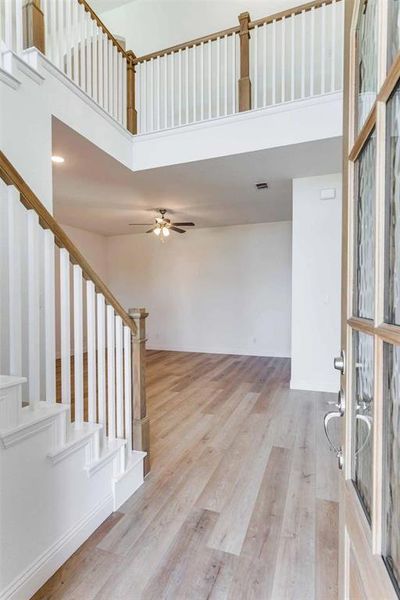 Staircase featuring a high ceiling, wood finished floors, and ceiling fan