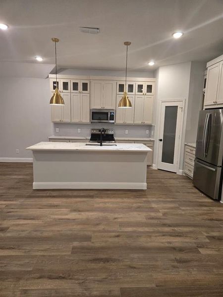 Kitchen with a kitchen island with sink, pendant lighting, and stainless steel appliances