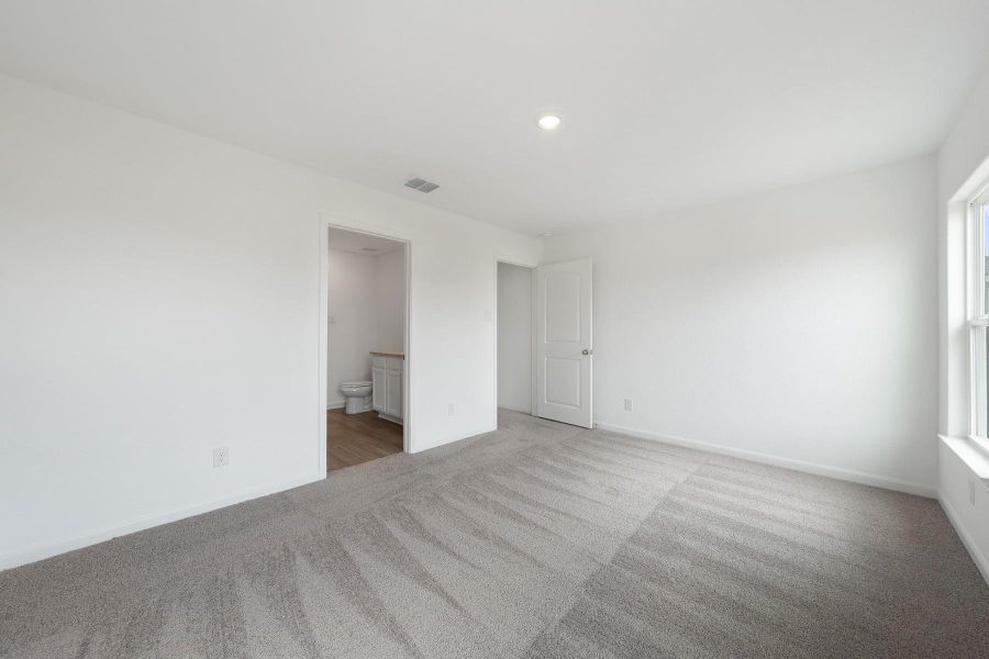 A spacious room with soft carpeting offers a private entryway to an adjoining bathroom.