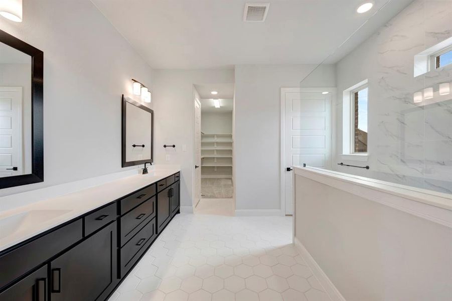 Full bathroom with a walk in closet, double vanity, and a marble finish shower
