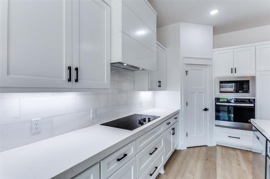 Kitchen featuring stainless steel appliances, white cabinetry, and decorative backsplash