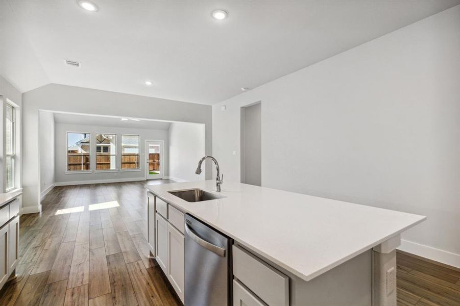 Kitchen with sink, dark hardwood / wood-style floors, stainless steel dishwasher, a kitchen island with sink, and white cabinets