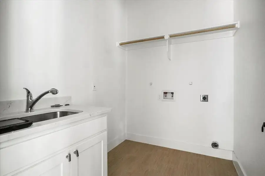 Laundry area featuring dark wood finished floors, hookup for a washing machine, electric dryer hookup, cabinet space, and hookup for a gas dryer