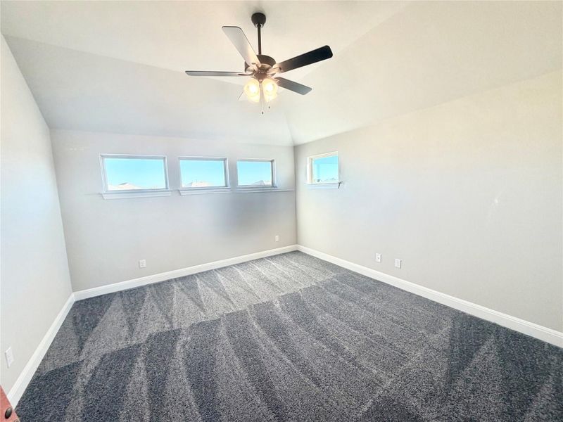 Carpeted spare room with lofted ceiling and a ceiling fan Carpeted spare room with lofted ceiling and a ceiling fan