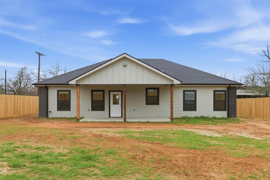 View of front facade with board and batten siding, roof with shingles, and covered porch