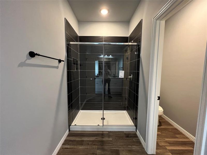 Bathroom with hardwood / wood-style floors, toilet, and an enclosed shower