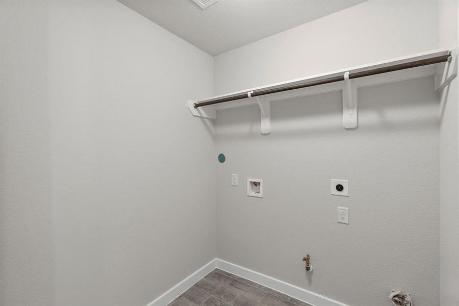 A perfect blend of functionality and comfort. Capture the essence of easy living with a first-floor laundry room, thoughtfully equipped with shelving for effortless organization. Both electric and gas connections available. Sample photo of completed home with similar floor plan. As-built interior colors and selections may vary.