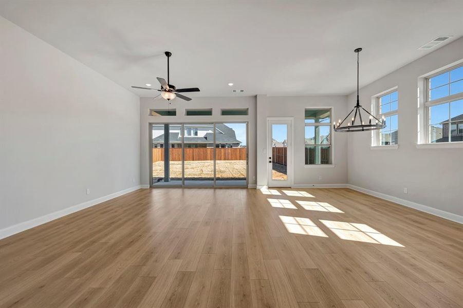 Unfurnished living room with light wood-style flooring, a ceiling fan, healthy amount of natural light, and hanging lights