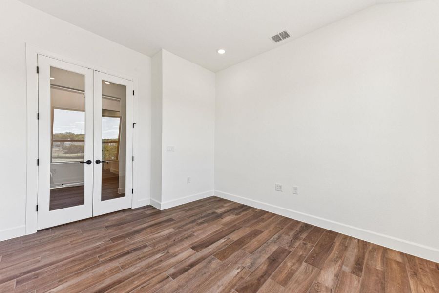 Spare room featuring french doors, dark wood-style floors, and recessed lighting