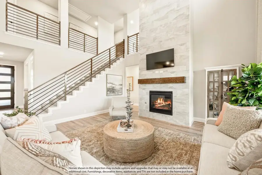 Two-story living room with stone fireplace, open staircase, and high ceilings