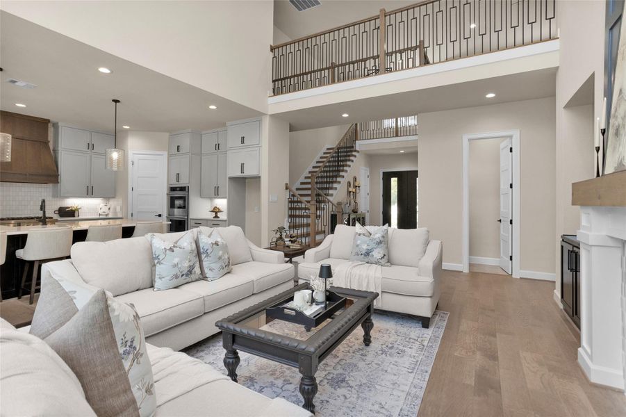 This open-concept space offers clear views from the living room into the modern kitchen and up the grand stairway to the loft-style landing above.
