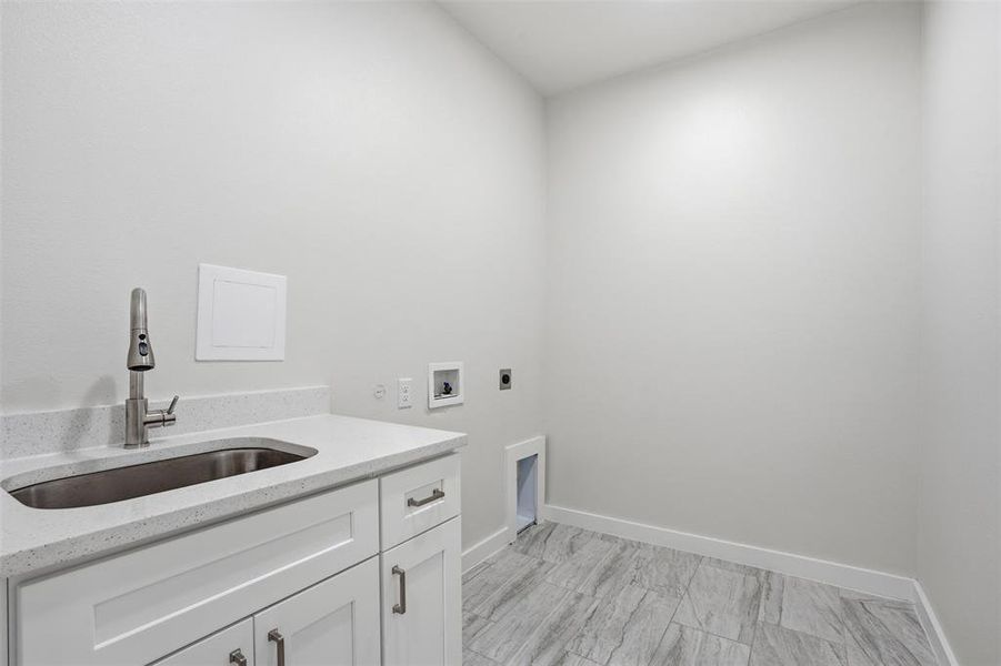 Utility room featuring a built-in sink with a pull-down faucet, white cabinetry with silver-tone hardware, and a light-colored countertop