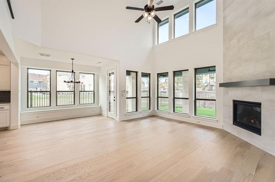 Unfurnished living room with a fireplace, a high ceiling, light hardwood / wood-style floors, and a wealth of natural light