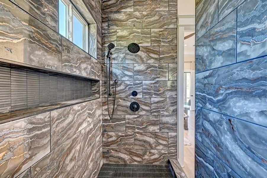 This photo showcases a modern shower with striking, earth-toned, marbled tiles. It features a sleek rainfall showerhead and built-in shelving, adding both style and functionality to the bathroom space.