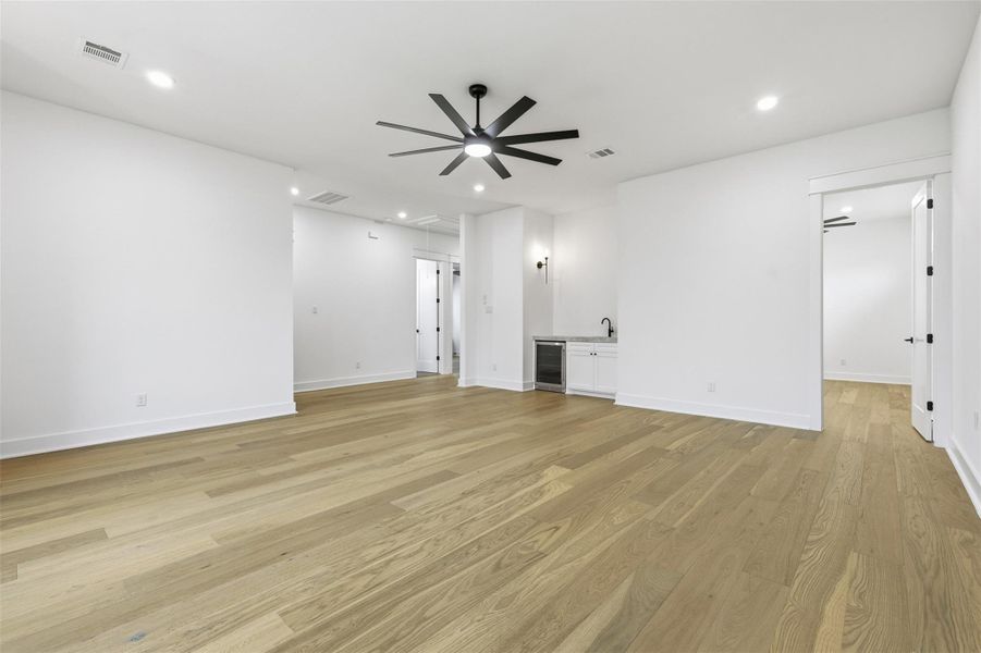 The second-floor family room with engineered hardwood flooring throughout, a functional wet bar, and endless possibilities for use as a game room, media room, or private lounge.
