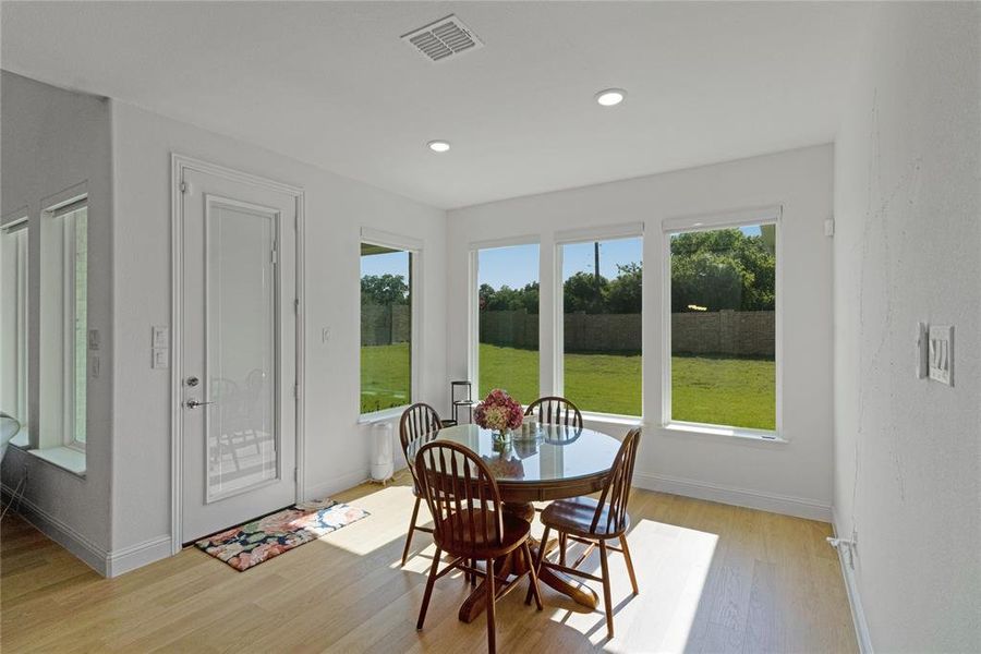 Sunlit dining area featuring wood-finish flooring and recessed lighting