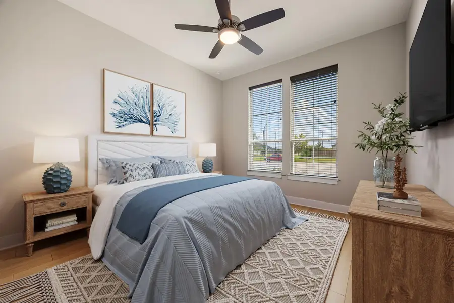 This inviting first-floor guest suite offers comfort and privacy, complete with an en suite bathroom for added convenience. Neutral tones and large windows fill the room with natural light, while a modern ceiling fan enhances comfort. Perfect for visitors, this space provides a restful retreat with its own private bath.