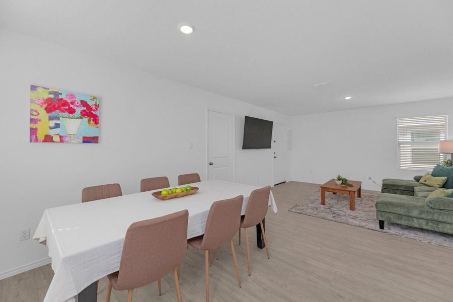 Dining area with light vinyl floors and recessed lighting.
