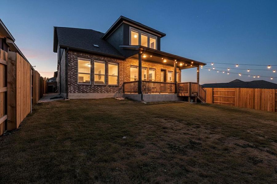 Back of property with brick siding and a fenced backyard